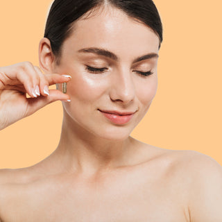 Woman holding Herbaly's Derma Hair, Skin & Nails + Biotin Capsule near her face, showing her glowing skin